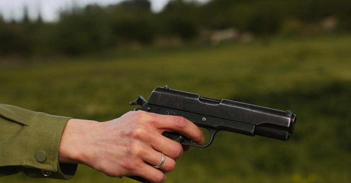A person holding a black semi-automatic handgun outdoors, highlighting a critical aspect of situational awareness in self defense training.